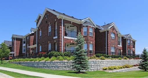 Luxury apartments with spacious balcony, red brick exterior, and beautiful landscaping at Rockledge Oaks Apartments in Lincoln, Nebraska