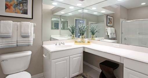 Luxury bathroom with tiled floors, glass shower, oval soaking tub, cultured marble vanity, and white cabinets in at Rockledge Oaks Apartments in Lincoln, Nebraska
