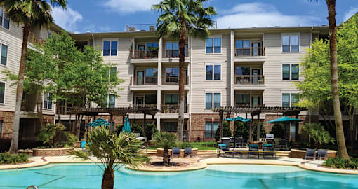 Luxury swimming pool with cabanas, poolside lounges, grilling stations, palm trees and beautiful landscaping at The Voss Apartments in Houston.