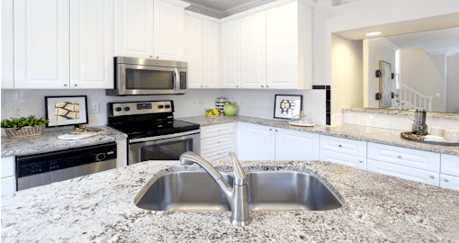Spacious kitchen with island, granite countertops, custom home cabinets, French doors, smooth glass top stove, spacious pantries, breakfast bar and stainless-steel appliances at Tuscany Row Townhomes in Houston.