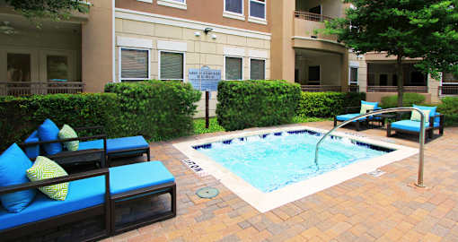 Luxury apartments with palm trees, spa, hot tub, spacious sundeck with poolside lounge chairs, beautiful landscaping, and fountains at Villa Piana Apartments in Dallas