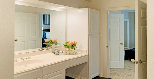Spacious bathroom with cultured marble vanity, spacious linen cabinet, white cabinets, and built-in vanity at The Lanesborough Apartments in Houston.