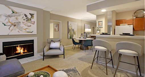 Spacious dining room area with mirror accent wall and kitchen with breakfast bar at Tuscany Lane Apartments in Houston.