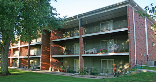 Apartments with brick exteriors, beautiful landscaping, lush landscaping, scenic views, large balconies, huge balconies, spacious balconies, and park-like setting with lots of trees at Alpine Village Apartments in La Vista, Nebraska