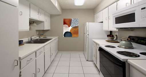 Bright white kitchen with gray wall color, white kitchen cabinets, lots of cabinet space, lots of counter space, and porcelain tile floors at The Inverness Apartments in La Vista, Nebraska