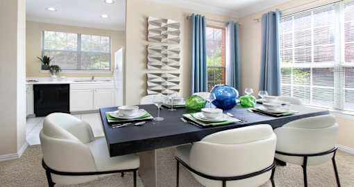Spacious dining room with oversized windows, u-shaped kitchen with white cabinets, and side-by-side refrigerator at Saddlebrook apartments in Urbandale Iowa