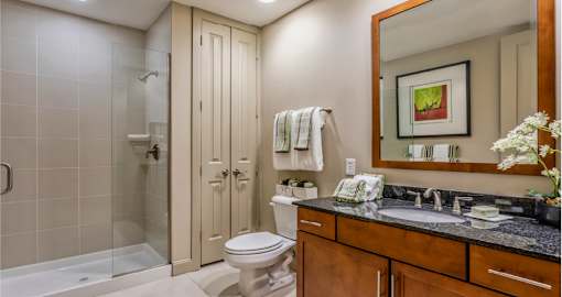 Luxury bathroom with granite countertops, glass shower and linen closet at Villa Piana Apartments in Dallas