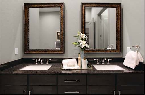 Double vanity bathroom with two mirrors and a black granite vanity top