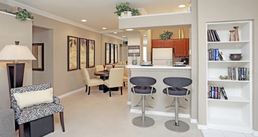 a living room with a table and chairs and a kitchen in the background
