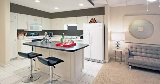 Large kitchen with lots of cabinet and counter space, white cabinets, colored feature wall, kitchen island, and prep island at Embassy Park Apartments in Omaha, Nebraska