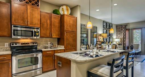 Luxury apartments next to the Galleria in Dallas with granite countertops, stainless steel appliances, built-in wine rack, kitchen island, and porcelain tile floor at Villa Piana Apartments in Dallas