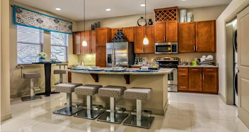 Luxury apartments with spacious kitchen with granite countertops, stainless steel appliances, built-in wine rack, kitchen island, and porcelain tile floor at Villa Piana Apartments in Dallas