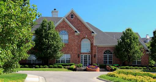 Luxury apartments with red brick exterior, lush landscaping, park-like setting, and scenic views at Lenox Village Apartments in Lincoln, Nebraska