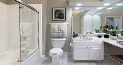Luxury apartments with spacious bathrooms with tiled floors, oval soaking tubs, built-in vanity, cultured marble vanity, glass shower and white cabinets in at Saddlebrook apartments in Urbandale Iowa