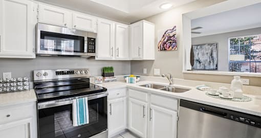 Luxury apartments with kitchens with white cabinets and stainless-steel appliances at The Saxony Apartments in Dallas