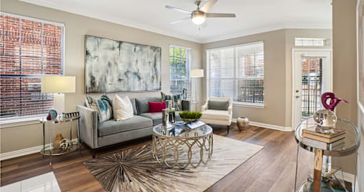 Spacious living room with wood plank floors, French door, and oversized windows at The Saxony Apartments in Dallas