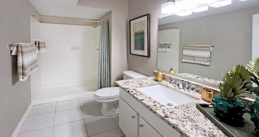 Spacious luxury bathroom with white cabinets, granite countertops, porcelain tile floor, soaking tub and tiled shower at Breckenridge Apartments in Omaha, Nebraska