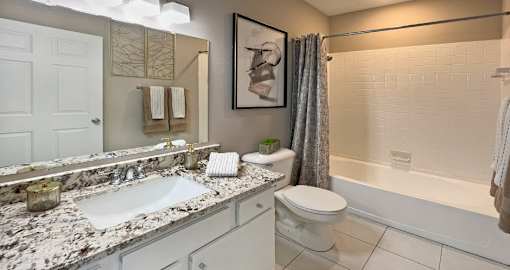 Spacious luxury bathroom with white cabinets, granite countertops, porcelain tile floor, soaking tub and tiled shower at Breckenridge Apartments in Omaha, Nebraska