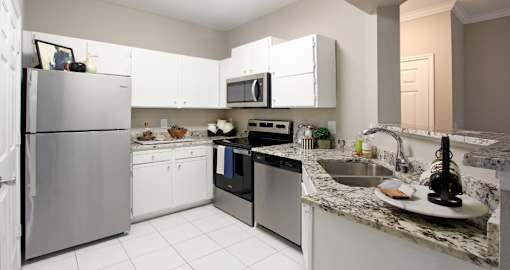 Spacious kitchen with white cabinets, granite countertops, stainless steel appliances, and porcelain tile floors at Breckenridge Apartments in southwest Omaha, Nebraska