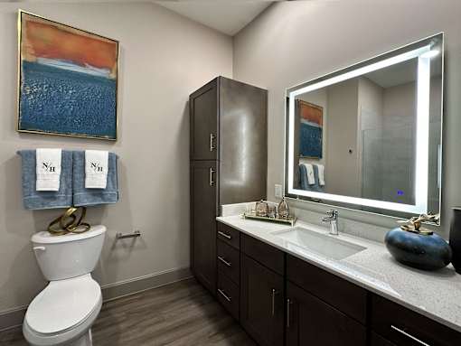 A bathroom with a toilet, sink, and a painting on the wall.