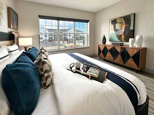 A bedroom with a large bed and a painting on the wall.