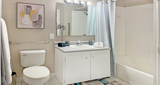 Spacious bathroom with white cabinets, linen closet, extra cabinet space, soaking tub and tiled shower at Breckenridge Apartments in Omaha, Nebraska