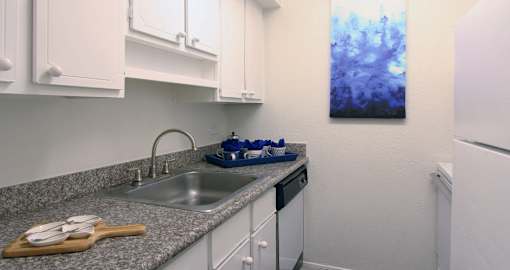 Bright white kitchen with granite countertops and hardwood floors at Briarwood Apartments in Houston.