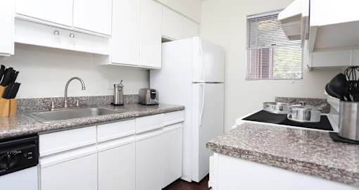 Kitchen with white cabinets, lots of counter space, lots of cabinet space, granite counter tops, and wood plank floors at Briarwood apartments in Houston, Texas