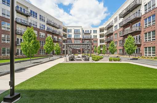 Luxury apartments with huge courtyard with lush landscaping, green space, outdoor seating area and pergola at Xenia Apartments in Golden Valley Minnesota