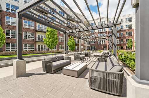 Luxury apartments with huge courtyard with modern pergola and seating area, lush landscaping, and green space at Xenia Apartments in Golden Valley Minnesota