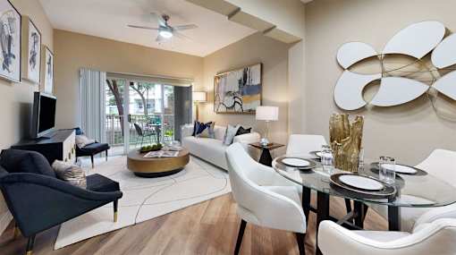 A modern living room with a glass table and white chairs.