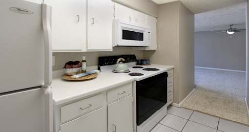 Bright white kitchen with gray wall color, white kitchen cabinets, lots of cabinet space, lots of counter space, spacious dining room and porcelain tile floors at The Inverness Apartments in La Vista, Nebraska