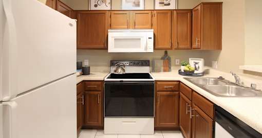 Spacious kitchen with honey brown toned cabinets, white countertops, and lots of counter space at Tuscany Lane Apartments in Houston Texas