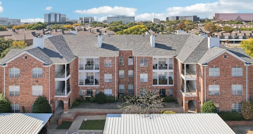 Gated luxury apartment community in north Dallas with red brick exteriors, covered parking, and beautiful landscaping at The Saxony Apartments