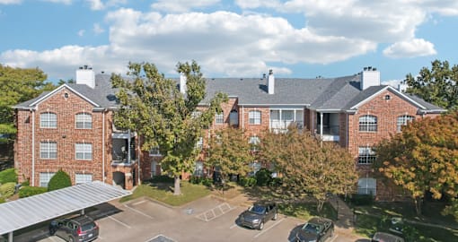 Gated luxury apartment community in north Dallas with red brick exteriors, covered parking, and beautiful landscaping at The Saxony Apartments
