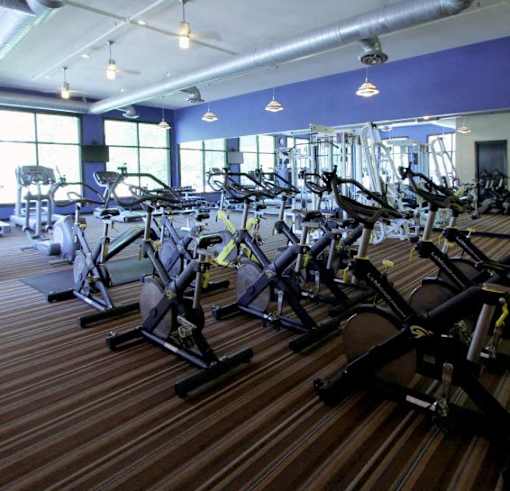 A gym with a variety of equipment including a leg press machine and a rowing machine.