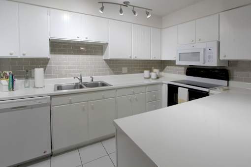 A kitchen with white cabinets and a white counter.