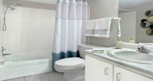 Bathroom with white cabinets, tiled floor and tiled shower with tub at Inwood Apartments in La Vista, Nebraska