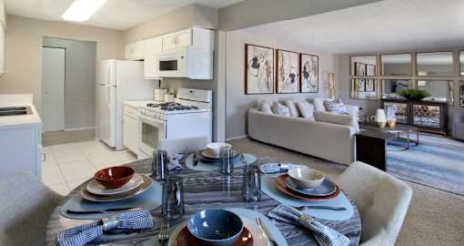 Spacious apartments with lots of natural light, spacious living room, spacious dining room, huge apartment, spacious floor plan, bright white kitchen, white kitchen cabinets, and gray wall color at Inwood Apartments in La Vista, Nebraska