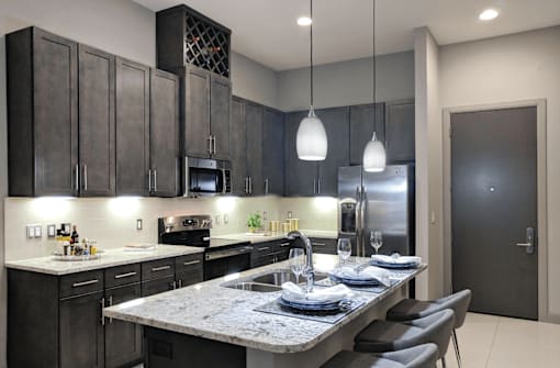 Luxury apartments with spacious kitchens with granite countertops, large granite slab island, built-in wine rack, and stainless appliances at Le Palais Apartments in Houston.