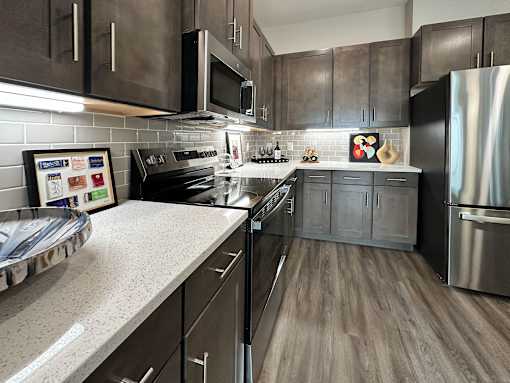 A modern kitchen with dark wood cabinets and stainless steel appliances.