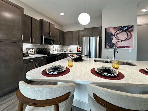 A modern kitchen with a large island and two chairs.