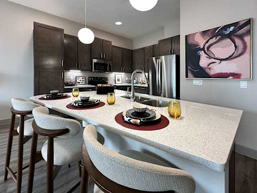 A modern kitchen with a dining table set for two.
