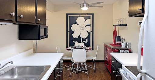 Fully equipped kitchen with black cabinets, ample countertop space, wood laminate flooring, and dining area at Kensington Woods Apartments