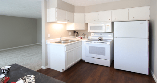 Apartments in central Omaha with spacious layout, spacious living room, bright white kitchen, gray wall color, and white kitchen cabinets at Kensington Woods Apartments in Omaha, Nebraska