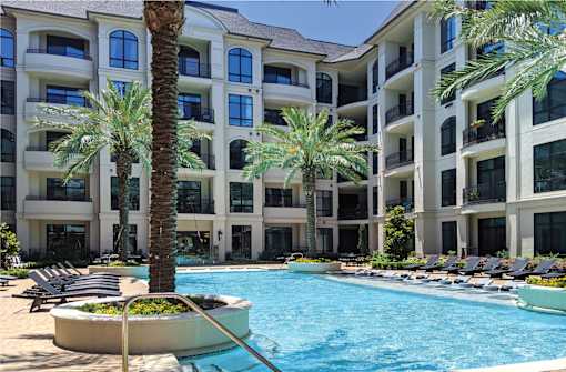 Luxury apartments with resort-style pool with palm trees, Baja shelf, fountains, lap lane, outdoor lounges, and grilling station at Le Palais Apartments in Houston.
