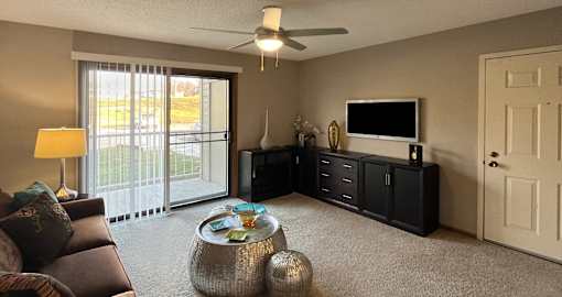 Spacious living room with large patio door windows at LionsHead Apartments in Omaha Nebraska