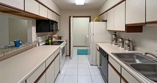 Kitchen with abundant countertop space and cabinets, granite breakfast bar, glass top stove, and separate laundry room at LionsHead Apartments in Omaha Nebraska