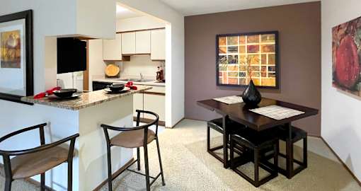 Dining room area with painted feature wall, granite breakfast bar, and kitchen with tiled floor at LionsHead Apartments in Omaha Nebraska