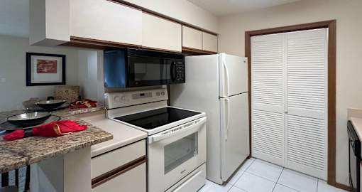 Kitchen with glass top stove, separate laundry room, tile floors, and granite breakfast bar at LionsHead Apartments in Omaha Nebraska